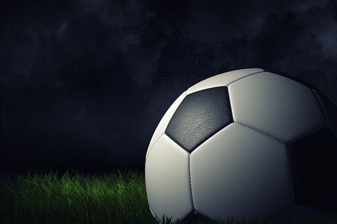 3D Football on Grass Against Dark Background