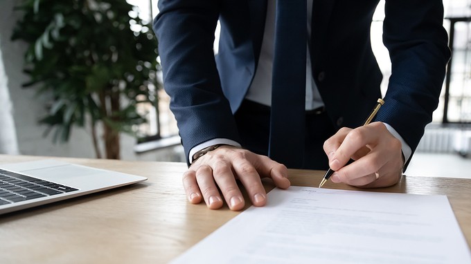 Businessman Standing at Desk Signing Contract